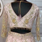 Embroidered blouse and skirt set on a mannequin against a decorative wall.