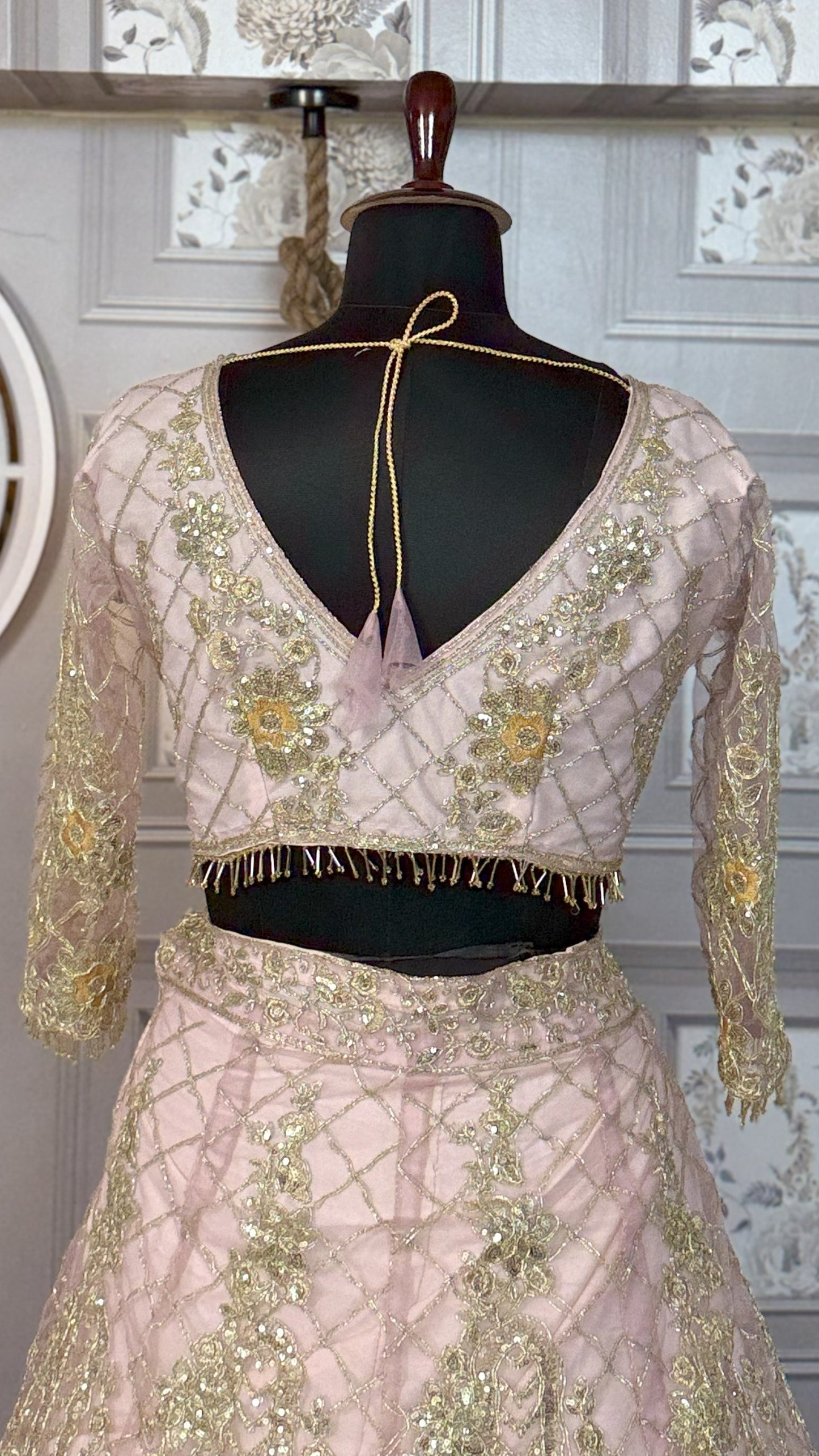 Embroidered blouse and skirt set on a mannequin against a decorative wall.
